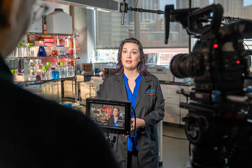 Chemistry Professor April Hill is interviewed by a TV news reporter in her laboratory.