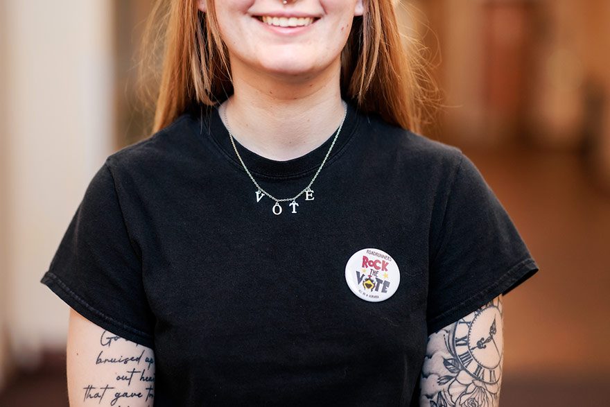 Student poses for photograph wearing 'rock the vote' button.