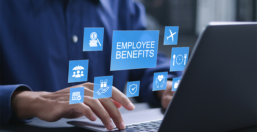 A employee sitting at a desk using a laptop with a graphic over the top saying "Employee Benifits".